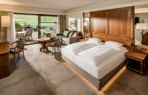 Zimmer 'Weinberg' im Hotel Haus am Hang: Doppelbett, Holzpaneel, Sitzbereich und große Fenster mit Blick ins Grüne.