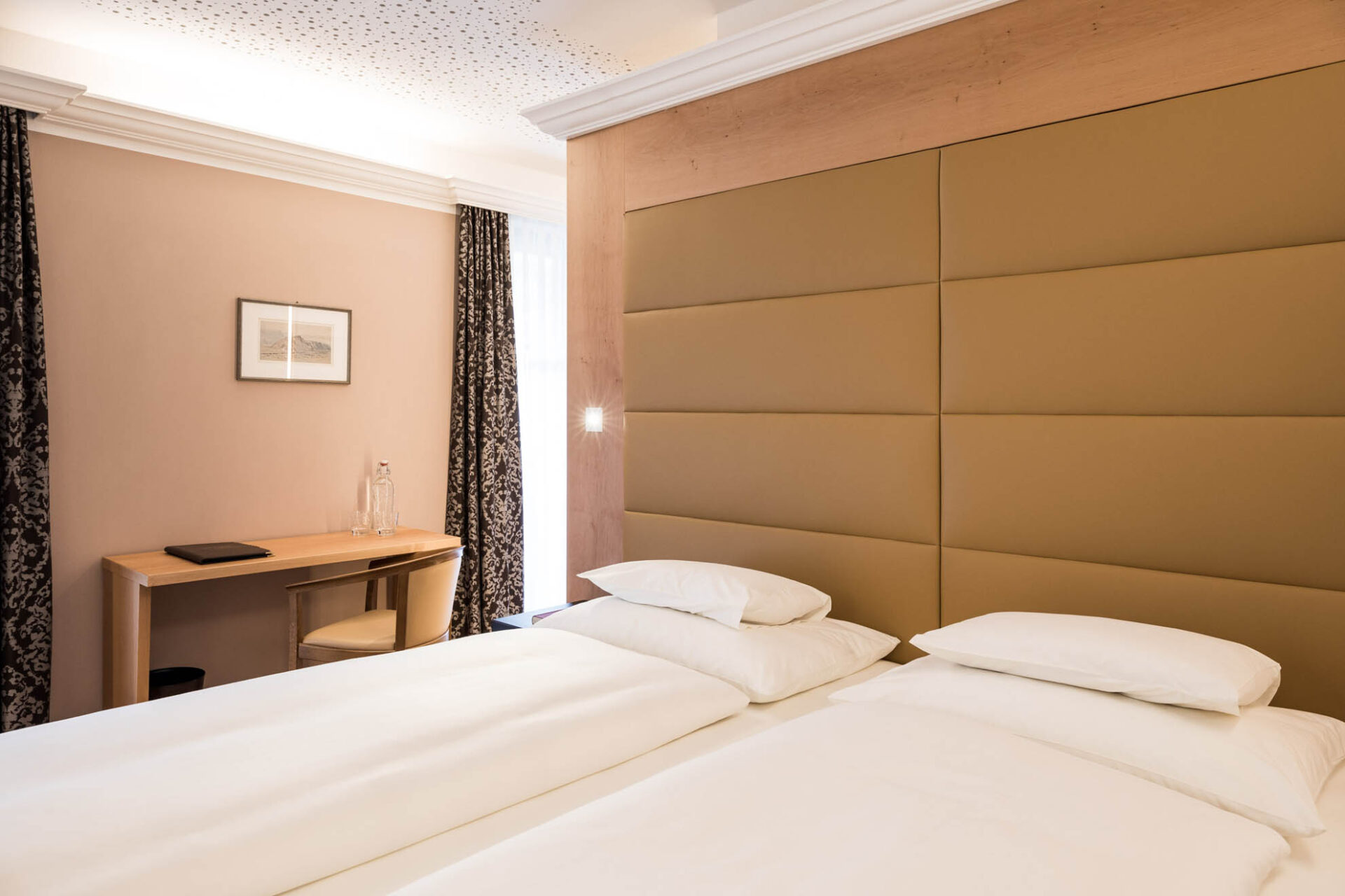 Zimmer Weinberg im Hotel Haus am Hang: zwei Betten, gepolstertes Kopfteil, Nachttischlampen, Schreibtisch, Vorhang